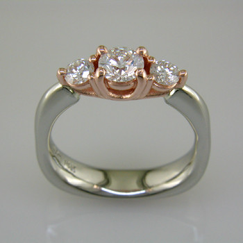 This delicate 3-stone ring is magical. 14 karat White Gold ring shaped with a soft square at the bottom, and 14 karat Rose Gold woven prong work on top. It feels soft and comfy on your finger. Set in the center is a 1/2 carat Ideal cut Diamond, and the sides total .34ct T.W. Ideal cut Diamonds.

Finger size 6 1/2. Can be sized, or custom made in your size.

Designed, and created in our studio by the artist Stuart J.