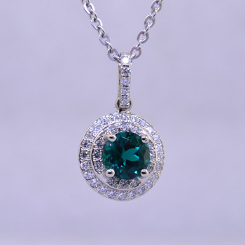 Elegant and timeless double halo pendant, in 14 karat white gold with .33ct. T.W. of Ideal cut diamonds, and an incredible 6.5mm deep green, brilliant cut Chatham Created Emerald. Includes a 1.3mm diameter 14 karat white gold wheat chain, 18 inches long.

Designed, and created in our studio by the artist Stuart J.

Chatham® Created Gemstones are grown in carefully controlled laboratory conditions. They are chemically and optically identical to their natural counterparts, yet cost much less. Because the environment in which they are grown is controlled, the imperfections often found in natural gemstones, are absent in Chatham® Created Gemstones. Because of this, and superior cutting, Chatham® gems exhibit the color and sparkle of the finest natural gems. Each one comes with a Certificate of Authenticity, and a Lifetime Warranty.