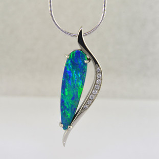 Like wearing a piece of Australia on your neck, this custom designed pendant is magical. From Andamooka, Australia, this vibrant blue-green 5.42ct. Opal doublet is cradled in 14 karat White Gold with .05ct. T.W. Ideal cut Diamonds. Includes a 1.3mm 14 karat White Gold smooth snake chain, 18 inches long.

Designed, and created in our studio by the artist Stuart J.

Our Andamooka opals are cut exclusively for us, and come directly from the mine in Andamooka, Australia. Our opal doublets are two layers, the top is the color layer, and the bottom is the opal host rock, or matrix. These layers are bonded together to make a stronger, more durable opal, and are guaranteed not to come apart or craze.