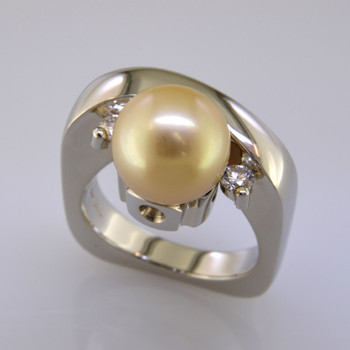 This one-of-a-kind Tahitian Pearl ring is truly a masterpiece. Modern, and elegant, this 14 karat white gold ring gently holds a spectacular 9.7mm golden colored Tahitian Pearl, framed by 2 round Ideal cut Diamonds totaling .20ct. Finger size 6. We can size it up or down about 1.5 sizes, or it can be special ordered in your finger size. Measures 3/4 inch wide.

Designed, and created in our studio by the artist Stuart J.