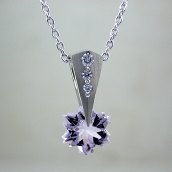 This Lavender Amethyst snowflake and Diamond Piercette® pendant will melt your heart. Dangling in 14 karat white gold, with an 8mm custom cut light lavender Amethyst snowflake and sprinkled with .07ct. T.W. Ideal cut Diamonds.
The Amethyst snowflake gemstone is custom cut, exclusively for us, in Canada. Includes a 14 karat white gold 1.0mm smooth snake chain, 18 inches long. Pendant measures 5/8" long.

Designed and handmade by the artist Stuart J.

A Piercette® is a patented method of setting, with a gemstone that moves. The gem is set so that it swivels with every movement of the wearer, exhibiting extra sparkle. 