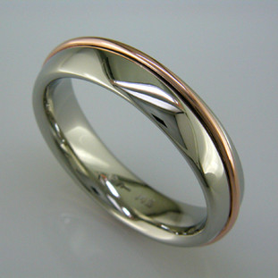 Just a little twist on the simple comfort fit man's wedding ring, this 6mm wide, 14 karat White Gold ring is wrapped in a 14 karat Rose Gold wire. Comfort fit to feel great when you are wearing it.

This wedding ring is priced in 14k gold, and can be made in any karat or color of gold, and in platinum. Please allow us 2 weeks to make it. It will be worth it!

Designed, and created in our studio by the artist Stuart J.