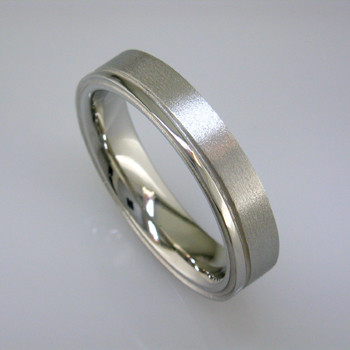 Sleek man's wedding band, 5mm wide, comfort fit, in 14 karat White Gold with a soft matte finish and a shiny edge. For the sophisticated man.

This is a special order item; please call with finger size, and allow two weeks for us to make it. It will be worth it!

Designed, and created in our studio by the artist Stuart J.