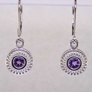 Blending traditional and modern, these earrings dazzle for day or night. Hand crafted in 14 karat white gold with sparkling 4mm Amethyst buff top gemstones dangling on lever backs. Earrings measure 1" long.  

Designed, and created in our studio by the artist Stuart J.