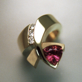 Beautiful, modern and fun. So unique, everyone will admire it. Made in 14 karat yellow gold with a sparkling 7.5mm Rhodolite Garnet Trillion gemstone, and .09ct. T.W. of ideal cut diamonds. Finger size 6.5. 

Call us for more information about how we can customize this design Just For You. Designed, and created in our studio by the artist Stuart J.