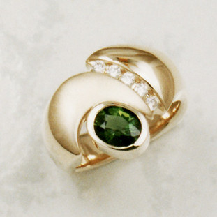You will be so stylish in this one of a kind gemstone ring, crafted in 14 karat yellow gold, with a dreamy deep green .98ct. oval Chrome Tourmaline, accented with .15ct .T.W. ideal cut diamonds. Beautifully finished with a contrasting satin treatment, for a sophistcated look. Finger size 6. Designed, and created in our studio by the artist Stuart J.