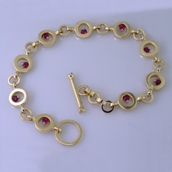 You will love this modern, fun circle bracelet, in 14 karat yellow gold, with nine 3mm round Fine Ruby Gemstones.  The custom designed toggle clasp has 2 round ideal cut diamond accents. Measures 7 3/4 inches long. Designed, and created in our studio by the artist Stuart J.
