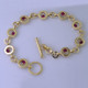 You will love this modern, fun circle bracelet, in 14 karat yellow gold, with nine 3mm round Fine Ruby Gemstones.  The custom designed toggle clasp has 2 round ideal cut diamond accents. Measures 7 3/4 inches long. Designed, and created in our studio by the artist Stuart J.