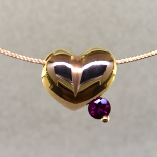 This lovely puffed heart pendant will make you feel happy every day. The ultimate fun heart with a deep red round rubellite tourmaline. This 14 karat yellow gold heart measures 1/4 inch long, and hangs on a 14 karat yellow gold 1mm wire, 16 inches long. 

Designed, and created in our studio by the artist Stuart J.