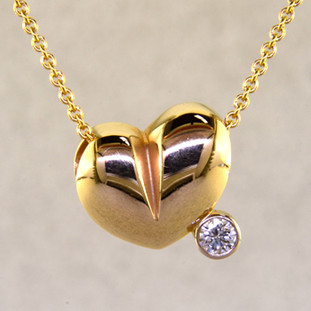 This lovely puffed heart pendant will make you feel happy every day. The ultimate fun heart with a .10ct. sparkling diamond. This 14 karat yellow gold heart measures 1/4 inch long, and hangs on a 14 karat yellow gold 1mm cable chain, 18 inches long. 

Designed, and created in our studio by the artist Stuart J.