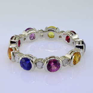  Want to brighten your day?  This amazing band will do it.  Feel special with this one of a kind eternity band with multi color sapphire gemstones.  All the colors of the rainbow,  This eternity band has .46ct. of sparkling diamonds and is surrounded by 9-round colorful sapphires.  This beautiful ring is made to order,so please allow 3-4 weeks for us to make it just for you. Call us for pricing.  Designed and created by master jeweler Stuart J.