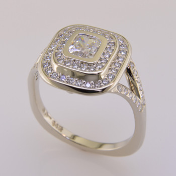 A diamond halo engagement ring with an exotic, sophisticated flare. Custom designed with .45ct. T.W. of ideal cut diamonds makes this ring sparkle like crazy. A beautiful GIA certified .60ct. cushion cut diamond is the focal point of the double halo, which creates a much larger look, for a lot less money than a large center diamond. With no prongs to worry about, this diamond engagement rign is smooth and easy to wear. This modern take on the traditional halo has split sides with diamonds for a very elegant look on the finger.  Custom made in our studio by the artist Stuart J.  

Finger size 6 3/4, but we can make this in any size you need. We can also customize this design any way you like, or even use your center stone.