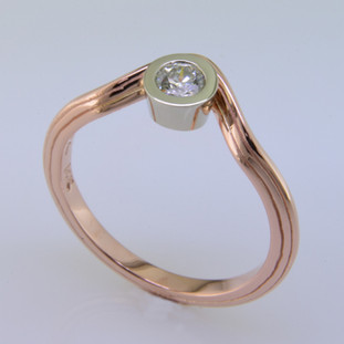 If you like unique, this rose gold diamond ring is for you. Clean simple lines make this ring feel light and modern. The beautiful .20ct. center diamond is floating in a 14karat white gold bezel. Wear it as a diamond engagement ring, or a fun pinky ring. Add our Dani Rose diamond eternity wedding band to complete the look. Call for details on how we can make it custom designed for you. Finger size 6 3/4.  

Custom made by the artist Stuart J.