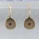 These sweet earrings shimmer when you wear them. Beautiful and rich 18 karat yellow gold medallion drops sprinkled with .11ct. of ideal cut diamonds set in a starburst pattern, with a glowing ruby in the center, hanging from wires. 12mm long.  

Designed and created in our studio by the artist Stuart J.