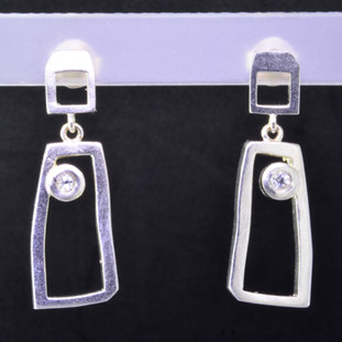 Fun, and funky earrings for the adventurous girl. Sterling silver dangles with rectangular shapes, bezel set with 2 colorless topaz gemstones resting on posts. Measures 1 inch long, and created in studio by french jeweler Sean Hill.