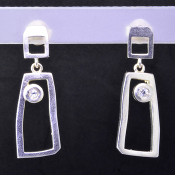 Fun, and funky earrings for the adventurous girl. Sterling silver dangles with rectangular shapes, bezel set with 2 colorless topaz gemstones resting on posts. Measures 1 inch long, and created in studio by french jeweler Sean Hill.