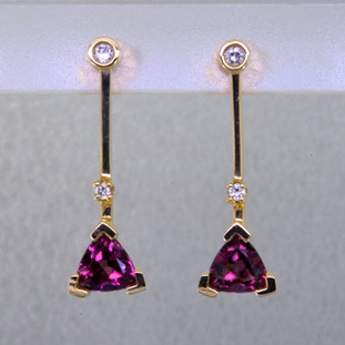 Fun and modern, these earrings dazzle for day or night. Hand crafted in 14 karat yellow gold with sparkling 6mm rhodolite garnet trillian gemstones and .10ct. of ideal cut diamonds hanging on posts.. Earrings measure 1" long.  

Designed, and created in our studio by the artist Stuart J.