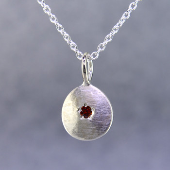 This sweet pendant shimmers when you wear it. Beautiful in sterling silver, this medallion with a glowing pink sapphire gemstone in the center, hanging from a sterling silver cable chain 18". Pendant measures 1/2 inch long.  Collect these and wear as a birthstone pendant too. Call for prices on other colors.

Designed and created in our studio by the artist Stuart J.