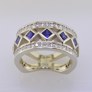 With this spectacular diamond and blue sapphire anniversary ring on your finger, you will feel like royalty, and be the envy of all of your friends. With .52 carats of Ideal cut diamonds, round diamonds cascading down the outside edges, and beautiful blue sapphire princess cuts down the center, Sparkle is this rings middle name. There are no prongs to catch, and it is very comfortable to wear. Made with a mix of round diamonds and princess cut diamonds, it is a feeling of traditional with a modern flare. This custom designed diamond anniversary ring is individually crafted to be Perfectly You. Call us for more information about how we can customize this design Just For You. 

Designed, and created in our studio by the artist Stuart J.

This diamond anniversary ring is priced in 14k gold, and can be made in any karat or color, and in platinum. Makes a great anniversary gift for 10, 20, 30 or more years together.