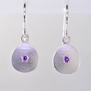 These sweet gemstone earrings shimmer when you wear them. Beautiful in Sterling silver, these medallions with bright amethyst gemstones in the center, hanging from sterling silver wires.  Earrings measure 3/4 inch long. Available in other colors. Please call for pricing.

Designed and created in our studio by the artist Stuart J.