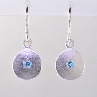 These sweet gemstone earrings shimmer when you wear them. Beautiful in Sterling silver, these medallions with bright blue topaz gemstones in the center, hanging from sterling silver wires.  Earrings measure 3/4 inch long. Available in other colors. Please call for pricing.

Designed and created in our studio by the artist Stuart J.
