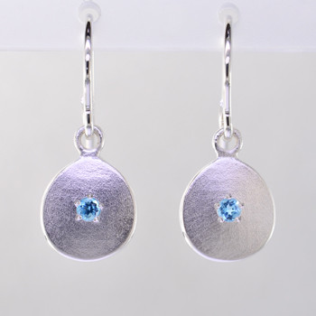 These sweet gemstone earrings shimmer when you wear them. Beautiful in Sterling silver, these medallions with bright blue topaz gemstones in the center, hanging from sterling silver wires.  Earrings measure 3/4 inch long. Available in other colors. Please call for pricing.

Designed and created in our studio by the artist Stuart J.