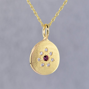 This sweet pendant has a special, hand applied finish that shimmers when you wear it. Beautiful and rich 14 karat yellow gold drop, sprinkled with .06 carat total weight of ideal cut diamonds, with a glowing rhodolite garnet gemstone in the center. Comes with an sixteen inch, 14 karat yellow gold rope chain. Pendant measures 5/8 inches long.   

Designed and created in our studio by the artist Stuart J.