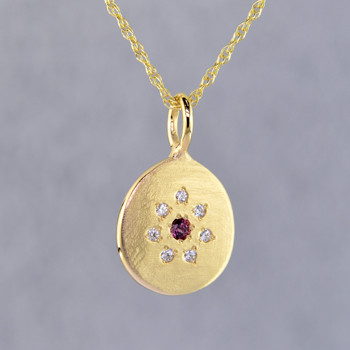 This sweet pendant has a special, hand applied finish that shimmers when you wear it. Beautiful and rich 14 karat yellow gold drop, sprinkled with .06 carat total weight of ideal cut diamonds, with a glowing rhodolite garnet gemstone in the center. Comes with an sixteen inch, 14 karat yellow gold rope chain. Pendant measures 5/8 inches long.   

Designed and created in our studio by the artist Stuart J.