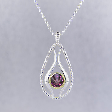 You will be captivated by this mix of modern and vintage in this elegant pendant.  The mix of sterling silver and 18K green gold is magical as this pendant comes together. The 18K bezel make this 8mm rhodolite garnet stratus gemstone pop as it is smooth and has a beautiful deep reddish color.The blend of the two metals is sophisticated, and fun, all at the same time. Perfect for any time of the day or night. This pendant hangs on a sterling silver bead chain, 20" long. The pendant measures 1 3/4 inches long.

Designed, and created in our studio by the artist Stuart J.