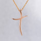 Elegant and modern, 14 karat rose gold curvy cross pendant, hanging from a 1mm, 14 karat rose gold diamond cut rope chain, 16 inches long. Cross measures 1 1/8 inches long, by 3/4 inches wide.

Designed and created in our studio by the artist Stuart J.