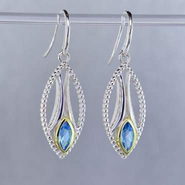 You will be captivated by this mix of modern and vintage in these elegant earrings.  The mix of sterling silver and 18 karat green gold is magical as these earrings comes together. The 18 karat bezels make these beautiful 8x4mm marquise, sea blue color, Swiss blue topaz gemstones pop! The blend of the two metals is sophisticated and fun, all at the same time. Perfect for any time of the day or night. These earrings hang on heavy sterling silver ear wires, and measure 1 1/2 inches long.

Designed and created in our studio by the artist Stuart J.