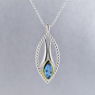 You will be captivated by this mix of modern and vintage in this elegant pendant. The mix of sterling silver and 18 karat green gold is magical as this pendant comes together. The 18 karat bezel make this beautiful 12x6mm marquise Swiss blue topaz gemstone pop. The blend of the two metals is sophisticated, and fun, all at the same time. Perfect for any time of the day or night. This pendant hangs on a sterling silver bead chain, 24" long. The pendant measures 1 3/4 inches long.

Designed and created in our studio by the artist Stuart J.