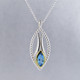 You will be captivated by this mix of modern and vintage in this elegant pendant. The mix of sterling silver and 18 karat green gold is magical as this pendant comes together. The 18 karat bezel make this beautiful 12x6mm marquise Swiss blue topaz gemstone pop. The blend of the two metals is sophisticated, and fun, all at the same time. Perfect for any time of the day or night. This pendant hangs on a sterling silver bead chain, 24" long. The pendant measures 1 3/4 inches long.

Designed and created in our studio by the artist Stuart J.