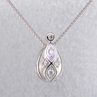 You will feel captivated by the feel of modern and vintage in this elegant diamond pendant. 14 karat white gold with .16 carats of sparkling ideal cut diamonds. This beautiful diamond pendant measures 1/2 inch long, and dangles on a 14 karat white gold 1.1mm wheat chain, 18" long.

Designed and created in our studio by the artist Stuart J.