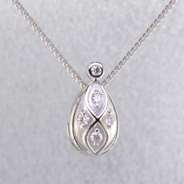 You will feel captivated by the feel of modern and vintage in this elegant diamond pendant. 14 karat white gold with .16 carats of sparkling ideal cut diamonds. This beautiful diamond pendant measures 1/2 inch long, and dangles on a 14 karat white gold 1.1mm wheat chain, 18" long.

Designed and created in our studio by the artist Stuart J.