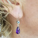 We picked these beautiful Zambian Amethyst drops because the color was so rich! We added beautiful light Blue Topaz for a perfect match. Handmade in 14 karat white gold, with blue topaz buff top gems set in bezels, and the amazing deep purple amethyst drops, making these earrings the perfect accessory to any outfit! These drop dangle earrings measure 1 1/4" long, and hang on 14 karat white gold wires.

Designed and created in our studio, by the artist Stuart J. Adelman.