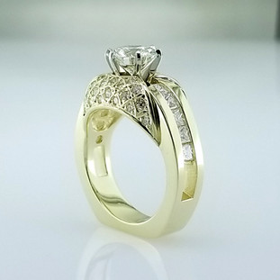Created to be old world and modern at the same time, this beautiful diamond engagement ring stuns! We created this ring in 18 Karat Yellow Gold, set the round ideal cut diamonds pave' style for an elegant look, added small princess cut diamonds down the sides to make it almost a carat and a half total weight, topped with a beautiful 1.53 carats round brilliant cut diamond. This ring is a statement piece! We can make this diamond engagement ring in any color metal, with any center stone.

Designed, and created in our studio by the artist, Stuart J. Adelman.