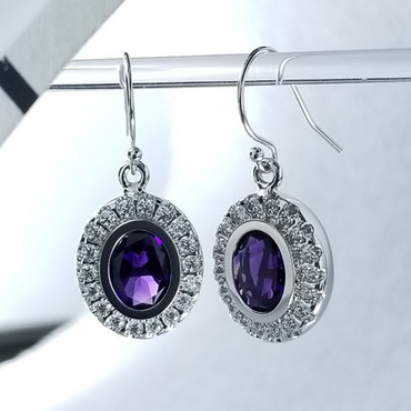 We created these timeless Amethyst and diamond halo earrings with a modern flare. There are no prongs to worry about, and our special setting style makes the 3/4 carat of super sparkly, Ideal cut diamonds look like twice the amount. Handmade in 14 karat White gold, two 9mm by 7mm oval, bezel set, deep purple amethysts create enough drama for evening, but not too much for every day wear. Dangling on handmade white gold wires, they measure about 1" long, and are designed and handcrafted by the artist, Stuart J. Adelman.

Call us for more information about how we can customize this design Just For You. 