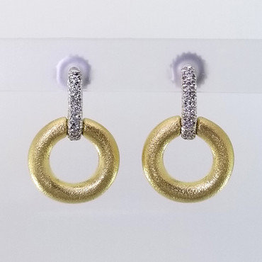 Inspired by natural colors and shapes, these sophisticated diamond circle earrings are crafted in rich 18 karat yellow gold, with 18 karat white gold tops, set with .11ct ct. total weight of sparkling diamonds. Hanging on 18 karat white gold posts. These earrings are truly a knock out piece. Measures 3/4 inches long. Exceptional in every way, and designed by the acclaimed jeweler Aaron Henry, in his California studio.