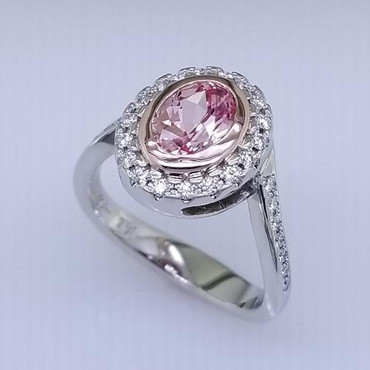 Here is an alternative to a diamond engagement ring.  This elegant halo diamond ring is the answer.  Created in 14 Karat White and Rose Gold, accented with .29ct .of our ideal cut diamonds and a 1.64 ct.  Created Champagne Oval Sapphire, bezel set in the center in warm Rose Gold. This modern halo ring has a split shank, and a squared shank making this ring unique.  Made in our studio by master artist Stuart J.
Please allow 2-3 weeks for delivery.