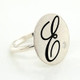 Cherish is our modern take on the timeless initial ring. It signifies how important you are, and symbolizes your name. With our modern round top, and our beautiful scripted initial, etched in black, you will surely be noticed wearing this. Shown here in sterling silver, set with our super sparkly .03ct. lab grown diamond. Measures 3/4 inch wide. This initial ring is also available in 14 karat yellow, white, or rose gold, and is available with all the birthstone colors.

Designed and created in our studio, by the artist Stuart J.