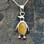 Hand crafted sterling silver penguin necklace with oval yellow butterscotch amber stone