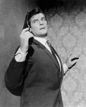 Roger Moore as Simon Templar holding up gun beside wall The Saint 8x10 photo