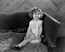 Shirley Temple sits on sofa smiling sweetly 8x10 inch photo