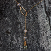 This gold and gemstone lariat necklace is pretty, feminine and dynamic. It is made of 14KT. Gold Filled delicate cable chain. A gemstone trio (1 - wire wrapped Prehnite Briolette and 2 Moonstone Rondelles) is threaded through a 14KT. Gold Filled Marquis Connector. This piece is 19" long, and can adjust between approximately 15"  to 17-1/2" around the neck.