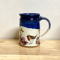 Hand-thrown mug with self-printed sepia toned decals including birds, wheat and other plants applied after glaze firing. A great combination of bright blue above the cream bird flower combination.  This beautiful round mug stands 4.5 in high by 3.5 in wide and holds about 14 oz of liquid.  Each mug will be unique.