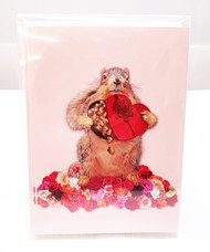 Nuts about Valentine's Day! Image is a pink card with a fuzzy squirrel holding a red heart-shaped box of chocolates surrounded by white, pink, & red roses.
Card reads: I'm nuts about you. Happy Valentine's Day.