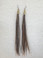 Extra long feather earrings made with natural rooster hackle feathers, featuring a mix of brown, black, and white tones, finished with gold-tone brass cone beads and titanium