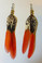 Pair of handmade feather earrings laid flat on a white background,