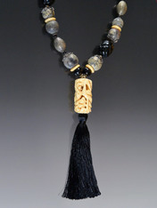 This spectacular black silk tassel necklace is anchored by an exquisitely hand-carved Ivory tube that I bought in San Francisco over 25 years ago.  I thought it was bone but a reputable gem dealer said ivory wasn't illegal at that time and from the color and weight he thought it was genuine ivory. This is paired with a necklace featuring, carved black jade, Bali silver, round bone and saucer beads, and antique jasper patterned beads, all gathered over the years.  It is a truly dramatic and unusual piece that you won't see anywhere.  24" silk tassel 6.5"

